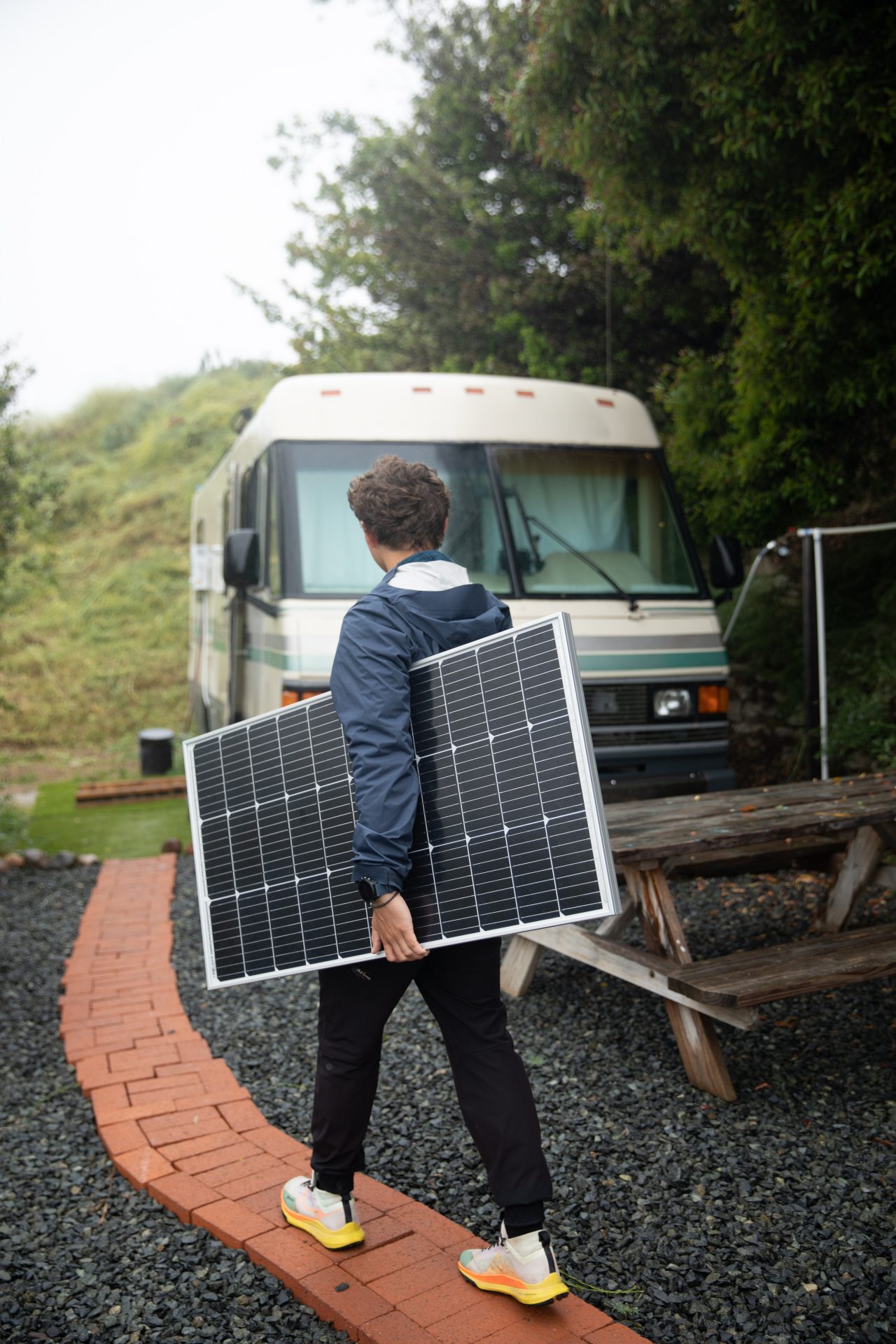 Ein Mann trägt ein Solarmodul zu einem kleinen Bus.
